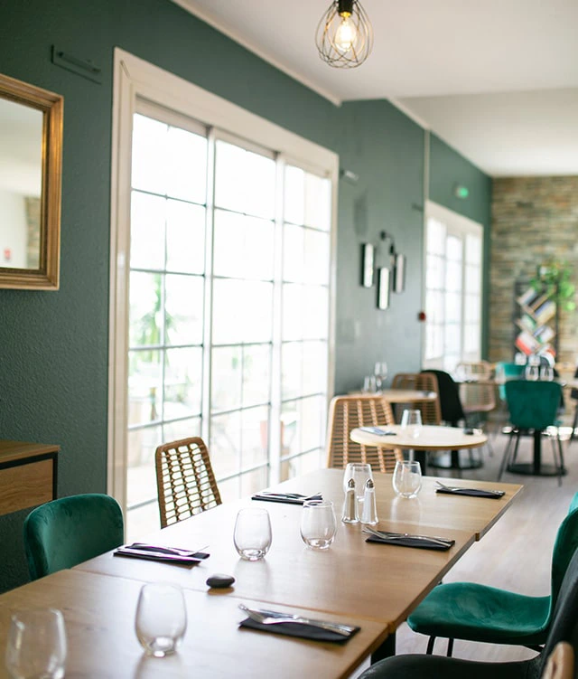 Sala de restaurante luminosa con grandes ventanales en el Hôtel Bordeaux Porte du Bassin